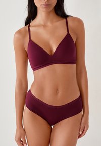 Set di reggiseno e mutandine color marrone scuro realizzato in tessuto liscio e elasticizzato. Il reggiseno presenta una scollatura profonda e spalline sottili; le mutandine hanno un design semplice.