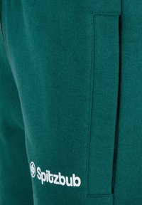 Teal Baumwoll-Sweatpants mit einer Seitentasche und einem weißen "Spitzbub"-Logo in der Nähe des Saums, mit einer weichen Textur und einem lockeren Design.