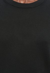 Tricou negru din bumbac, cu guler rotund și textură netedă. Are un design simplu, fără logo-uri sau modele vizibile.