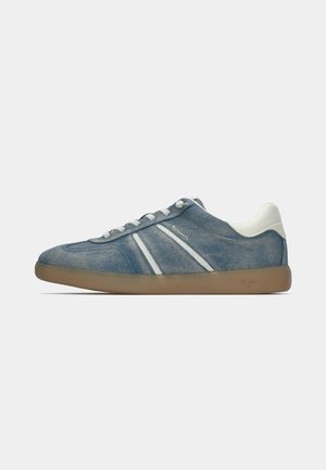 Sneaker en denim bleu bas profil avec des lacets blancs, un onglet de talon blanc, deux rayures blanches et une semelle en caoutchouc brun clair.