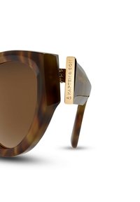 Bruna sköldpaddsmönstrade solglasögon med en djärv, geometrisk ram. Har gradientbruna linser och en guldfärgad metalldetalj vid skalmen.