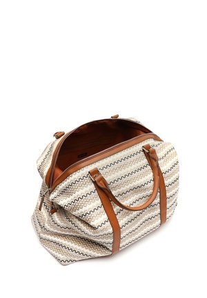 Beige og hvid mønstret tote taske med brune læderhåndtag og detaljer, lynlåslukning og rummelig inderside. Zigzag-design fremhæver stoffet.