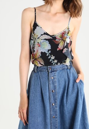 Camicetta nera con fiori e spalline sottili, caratterizzata da motivi floreali colorati, abbinata a una gonna in denim a pulsante lunga fino al ginocchio.
