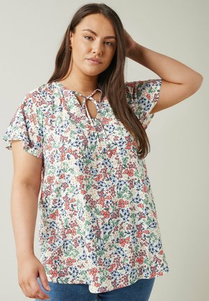 Floral blouse in cream, featuring a floral pattern in red, blue, and green. Keyhole neck detail and ruffled short sleeves. Cotton blend fabric.