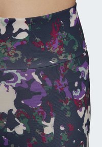 High-waisted leggings made of stretchy fabric, featuring a colorful abstract pattern in dark green, purple, and beige against a navy background.