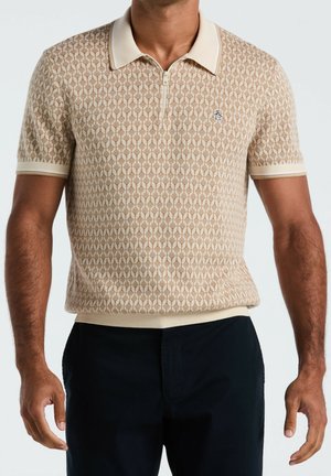Mand iført beige mønstret kortærmet poloshirt med lynlåsføring og lille logo på brystet, kombineret med sorte bukser.