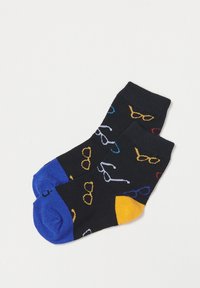 Schwarze Socken mit bunten Brillenmustern in Gelb, Rot, Blau und Weiß. Mit blauen und gelben Akzenten an Ferse und Zehen.
