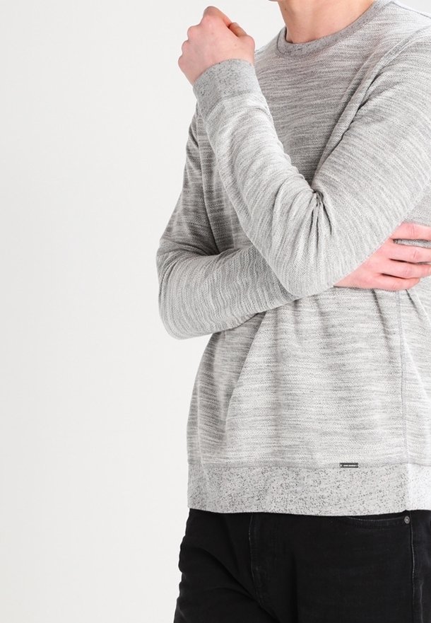 Suéter gris de manga larga con un patrón texturizado, cuello redondo y dobladillo en contraste. Fabricado con una tela suave y de corte relajado.