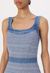 Denim obleka s kvadratnim izrezom in širokimi naramnicami. Teksturirana modra tkanina s prilegajočim pasom in rahlo razširjenim krojem.