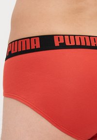 Piros pamut alsónadrág fekete derékkal, rajta feltűnő piros "PUMA" logóval. Sima tapintás, feszes fazon és varrott szélek.