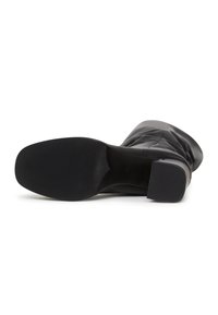 Botine negre până la gleznă, cu un exterior din piele netedă, vârf pătrat și toc gros. Talpa are o textură pentru aderență. Fără modele sau accente vizibile.