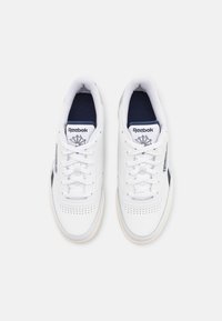 Valged nahast sneakerid mereväe aktsentidega, perforatsioonidega külgedel ja valgete paeltega. Brändi logo nähtav keelel ja küljel. Kreemjat värvi tald.