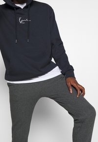 Navy hooded sweatshirt with white logo, cozy fabric, kangaroo pocket, paired with gray sweatpants in soft knit, featuring tapered legs.