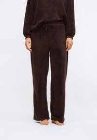 Hnědé huňaté volné kalhoty na domácí nošení s elastickým pasem, širokými nohavicemi a měkkou strukturou, navržené pro pohodlí a odpočinek.