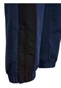 Marinblåa träningsbyxor med en svart sidopanel, elastiska muddar och en mjuk textur, designade för komfort och rörelsefrihet.