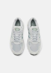 Ljusgrå sneakers i mesh- och mockamaterial. Har tre turkosa ränder och vita sulor. Rundad tå och snörning.