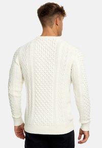 Cremefarbener Kabelstrickpullover mit verschiedenen strukturierten Mustern, gerippten Bündchen und Saum sowie einem klassischen Rundhalsausschnitt.