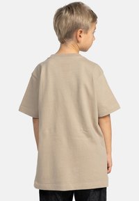 Beige bomull t-shirt med kort ärm och avslappnad passform. Enkel design, rena linjer och en mjuk textur. Vy från baksidan.