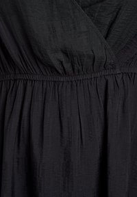 Melna kleita ar teksturētu audumu, kas ir ar apkārtēju dizainu un elastīgu jostu. Materiālā ir smalkas vertikālas svītras un mīksta kritums.