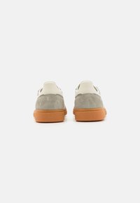 Grå mocka och vit läder sneakers med en texturerad orange gummisula, med en klassisk låg design och minimalistisk stil.