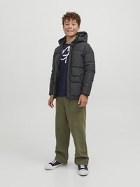Black puffer jacket with a hood, quilted design, paired with a navy sweatshirt and olive-green pants. Footwear includes black sneakers.