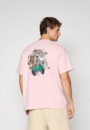 Light pink cotton t-shirt featuring a graphic of a dog and an owl in a golf cart, surrounded by golf clubs and a green accent color.