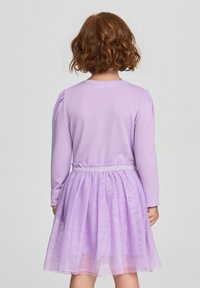 Abito viola con top a maniche lunghe e gonna in tulle. La gonna ha una texture luccicante. Vita elasticizzata con dettagli argentati.