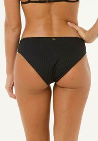 Bikini bottom nero a coste con design a vita bassa. Presenta un'etichetta del marchio discreta sul retro e una consistenza liscia.