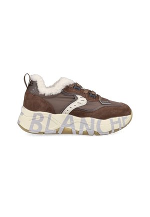 Vue latérale d'une basket marron et beige avec une doublure blanche duveteuse et un grand texte sur la semelle.
