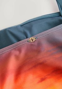 Kleurgradaties in stof in tinten van oranje en blauw, met een gouden cirkelaccent en een gladde, textuurrijke afwerking.