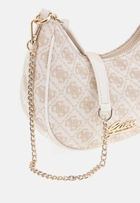 Beige handtas met patroon van gestructureerde stof, gouden accenten en een kettingriem. Voorzien van een ritssluiting en een geperst logo.