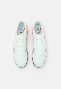 Light green athletic shoes with a textured upper, orange accents, a blue sole, and white laces. Features a Nike logo on the side.