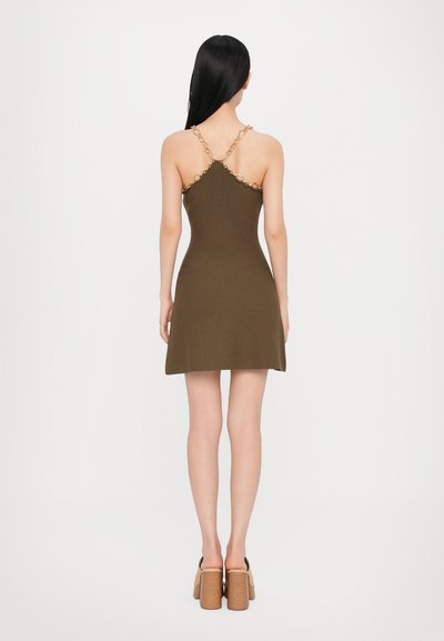 Brauner ärmelloser Dress mit tailliertem Oberteil und schwingendem Rock. Einzigartige Kettengliederakzente an den Trägern. Glatte Stoffstruktur.