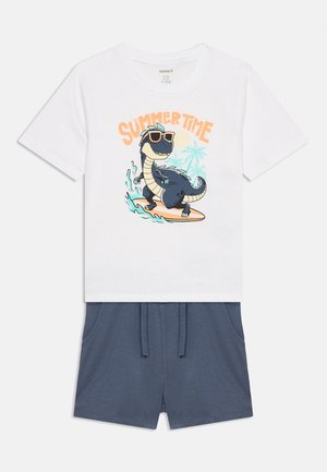 Biała koszula z krótkim rękawem z nadrukiem dinozaura surfującego na desce i napisem "SUMMER TIME", w zestawie z niebieskimi spodenkami ze sznurkiem.