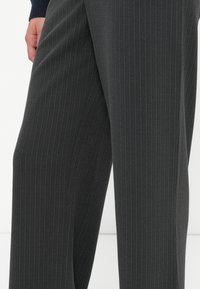 Dark grey pinstripe trousers made of suiting fabric. Features a smooth texture and tailored fit, extending to the ankle.