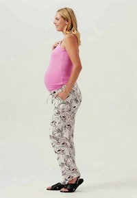 Graviditetsoutfit bestående af en tætsiddende lyserød tanktop og lette, mønstrede bukser med et blomsterdesign i hvid, grøn og sort.