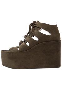 Sandales compensées en suede marron avec des découpes ouvertes, des lacets à l'avant et un talon haut et effilé pour un surélévation supplémentaire.