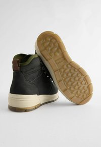 Czarne i oliwkowe wysokie sneakersy z teksturowanej skóry i gumową podeszwą. Charakteryzują się wyściełanym kołnierzem oraz wzorzystą podeszwą zewnętrzną dla lepszej przyczepności.