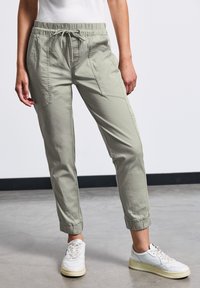 Ljusgröna, avslappnade byxor med elastisk midja, dragsko och elastiska muddslut. Har framfickor med en slät, textural yta.