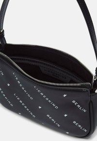 Czarna skórzana torba crossbody z srebrnym zipperem, z nadrukiem "LIEBESKIND BERLIN" oraz małym wzorem logo, częściowo otwarta, ukazująca wewnętrzną metkę.
