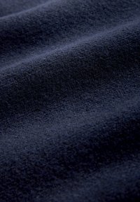 Dark blue fabric with a soft, textured surface and gentle folds creating subtle shadows and highlights.
