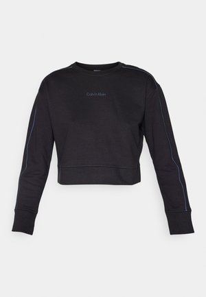 Black cropped sweatshirt, cotton blend, featuring long sleeves, crew neckline, and contrasting blue stitching along the sides. Calvin Klein logo embroidered.