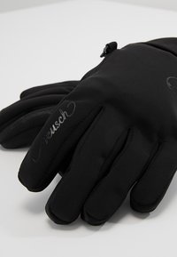 Guanti neri realizzati in tessuto morbido ed elastico con una texture liscia. Caratteristiche includono cinque dita e una piccola chiusura con zip sul polso.