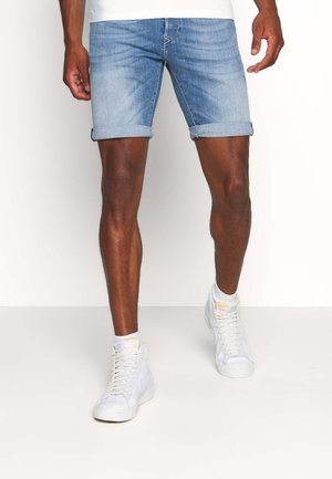 Lichtblauwe denim shorts met opgerolde boorden, uitgevoerd in een standaard pasvorm. Gecombineerd met witte hoge sneakers. Soepele textuur en casual ontwerp.