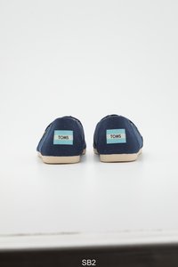 Marineblauwe canvas instapschoenen met beige rubberen zolen. Voorzien van lichtblauwe "TOMS" labels op de hielen. Eenvoudig, afgerond ontwerp met gestikte naden.