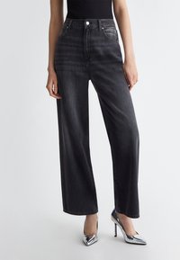 Jeans a vita alta e gambe larghe in denim grigio scuro, con chiusura a bottone, tasche frontali e una finitura pulita senza effetti di usura.