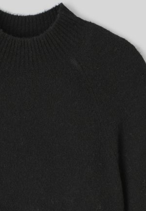 Pull en maille noir avec un col rond côtelé, une texture douce et des coutures droites, présentant un design simple sans embellissements.