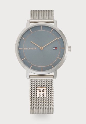 Round silver watch with a blue textured dial, rose gold accents, and a silver mesh strap featuring a logo detail.