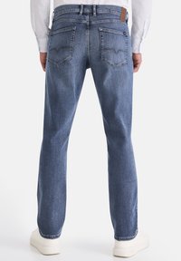 Blaue Jeans aus Denim mit geradem Schnitt, ausgestattet mit Gesäßtaschen mit dekorativen Nähten und einem braunen Lederpatch am Bund.