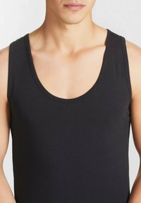 Top senza maniche nero realizzato in morbido tessuto elasticizzato. Presenta un collo e delle maniche larghe, una forma aderente, con una texture liscia e un design minimalista.